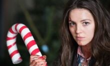 A blood-spattered Anna, played by Ella Hunt, holds a large candy cane weapon.