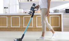 Woman using the JASHEN cordless vac on what looks to be her kitchen floors