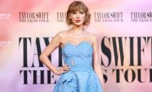 Taylor Swift posing on The Eras Tour Movie premiere red carpet in a light blue floral dress.