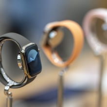 Three Apple Watches lined up on display stands in a store.