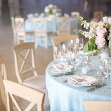 An empty table at a wedding, served with cutlery, flowers and crockery and covered with a tablecloth. 