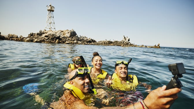 Four people snorkeling and taking selfie in ocean