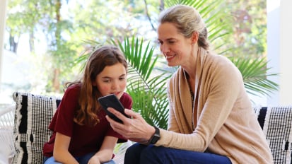 woman and girl looking at smartphone together