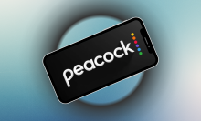phone with Peacock app logo on screen and blue background