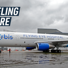 A long shot shows the side of Orbis's Flying Eye Hospital plane. Caption reads "traveling eyecare."