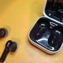 earbuds with stems and their case against a yellow background