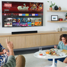 Four people sitting in living room with snacks and TV on wall with streaming apps on screen