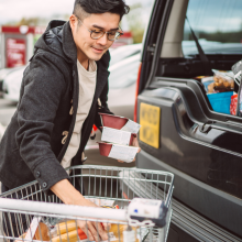 man putting groceries into trunk of car