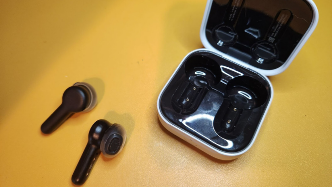 earbuds with stems and their case against a yellow background