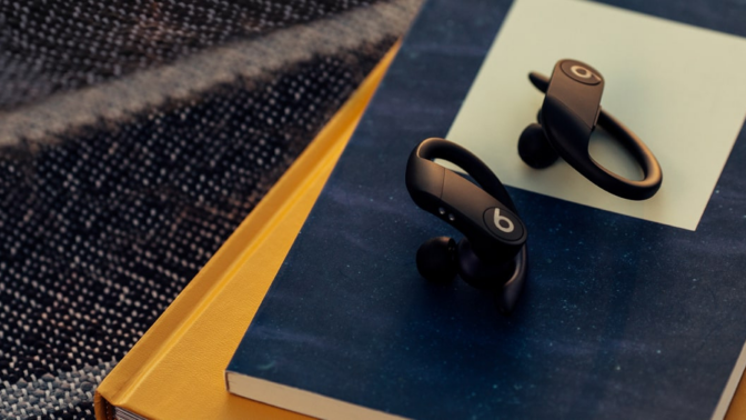 Powerbeats Pro earbuds in black laying on stack of books